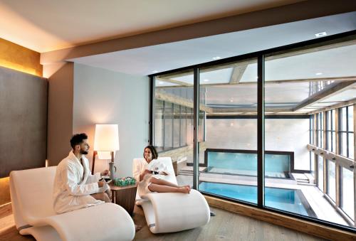 a man and woman sitting in a hotel room with a pool at MGM Hôtels & Résidences - Résidence Chalets Elena in Les Houches