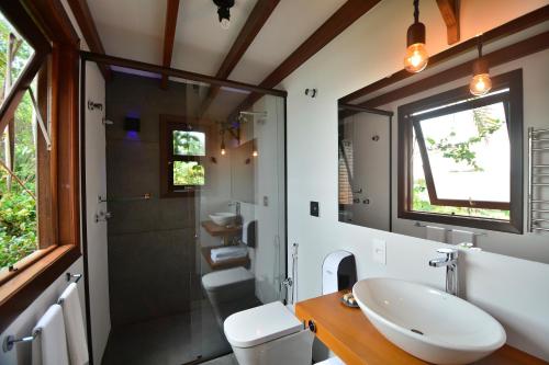 a bathroom with a sink and a toilet and a shower at Villa Gardena Suites in Praia do Rosa