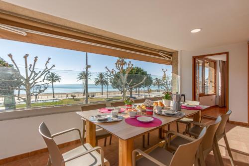 a dining room with a table and chairs and a view of the beach at Apart-rent Apartament Av Rhode 2006 in Roses