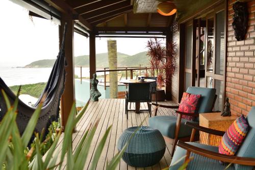 a porch with a hammock and a table and chairs at Villa Gardena Suites in Praia do Rosa