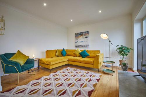 a living room with a yellow couch and two chairs at Host & Stay - Strathview in Hexham