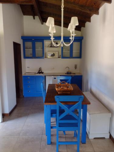 cocina con armarios azules, mesa y sillas en Abril Village en Tandil