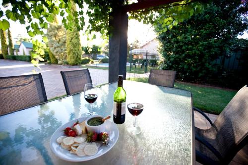 a table with a plate of food and a bottle of wine at Country Apartments in Dubbo