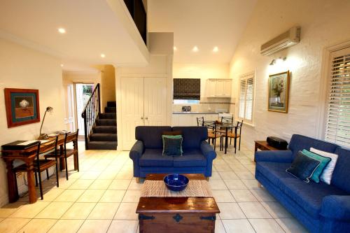 a living room with two blue couches and a kitchen at Country Apartments in Dubbo