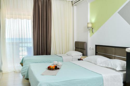 two beds in a hotel room with a bowl of fruit at Vento di Mare in Perea