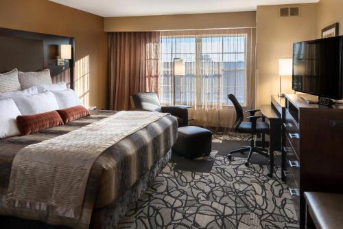 ClubHouse Hotel & Suites Fargo في فارغو: غرفة فندقية بسرير وتلفزيون بشاشة مسطحة