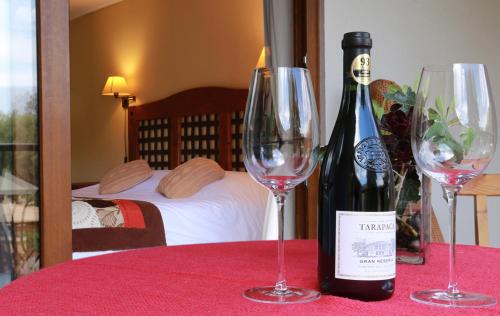 a bottle of wine sitting on a table with two wine glasses at SEL Lodge - Aventura y Descanso in San José de Maipo