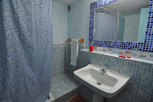 a blue tiled bathroom with a sink and a mirror at RNET - IR 7-29 Studios Roses Costa Brava in Roses