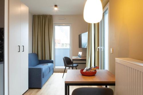 a living room with a blue couch and a table at Brera Serviced Apartments Frankfurt West in Frankfurt/Main