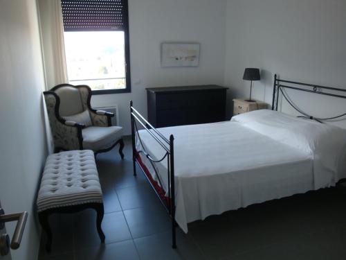 a bedroom with a bed and a chair and a window at LE CARRE MONTFORT in Vaison-la-Romaine