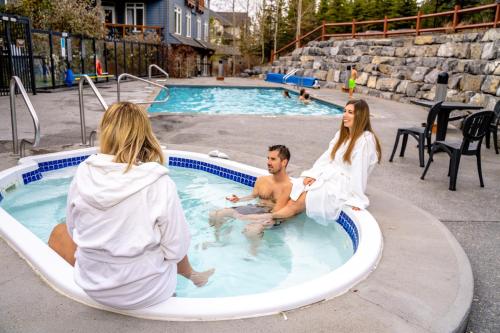 a man and a woman sitting in a swimming pool at Blackstone Mountain Lodge by CLIQUE in Canmore