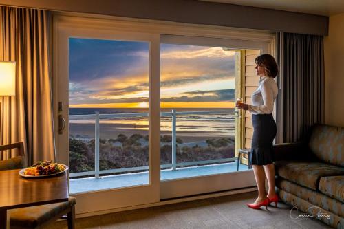 a woman standing in front of a window looking out at the ocean at Driftwood Shores Resort in Florence