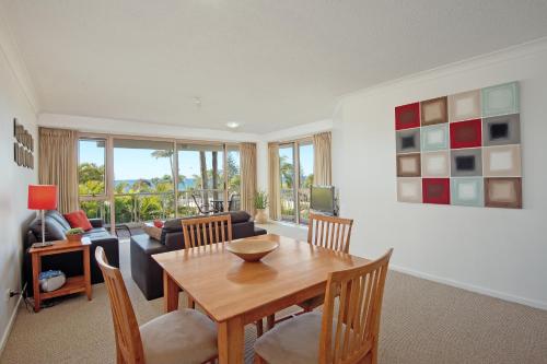 a living room with a wooden table and chairs at Osprey Apartments in Mooloolaba