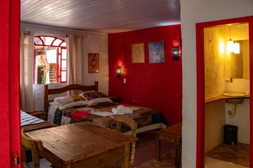 um quarto vermelho com duas camas e uma mesa em Espaço João Mineiro em Tiradentes