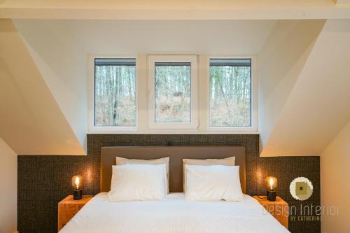 a bedroom with a bed with three windows at Plein la vue in Barvaux