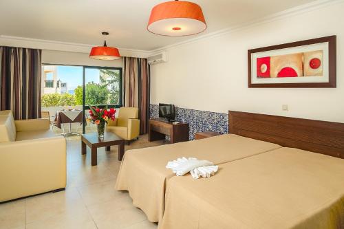 
a hotel room with two beds and a table at Cerro Mar Atlantico & Cerro Mar Garden in Albufeira
