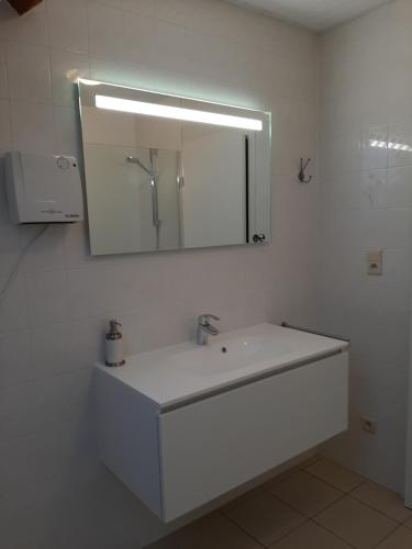 a white bathroom with a sink and a mirror at Huis Pimpernel in Bredene