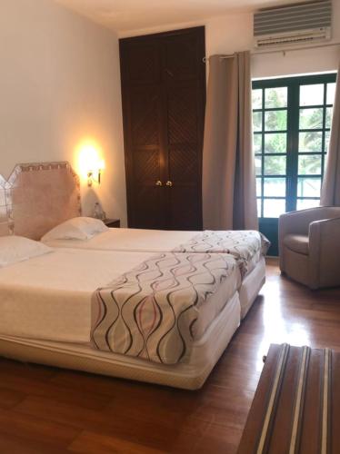 a bedroom with a large bed and a chair at Hotel Castelo de Vide in Castelo de Vide