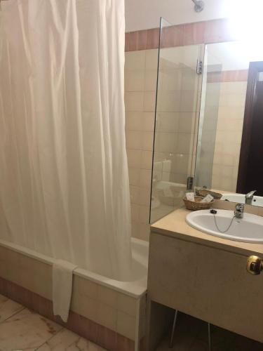 a bathroom with a shower curtain and a tub and a sink at Hotel Castelo de Vide in Castelo de Vide