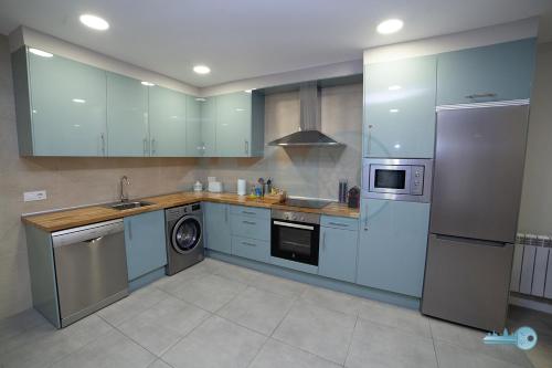 a kitchen with blue cabinets and a washer and dryer at Apart A 5 min de Laurel coqueto y en pleno centro Vivienda de uso Turistico in Logroño