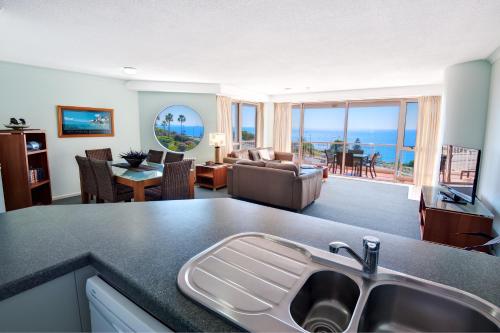 a kitchen and living room with a view of the ocean at Osprey Apartments in Mooloolaba
