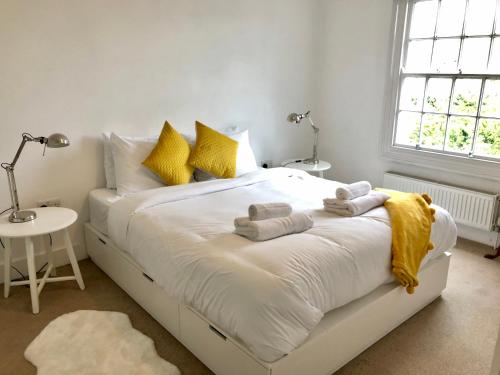 Un dormitorio con una cama blanca con toallas. en Charming Cottage & Garden - central Brighton! en Brighton & Hove