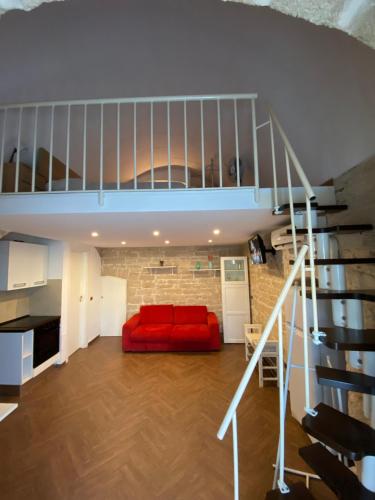 a living room with a red couch and a staircase at La persiana sul mare in Giovinazzo