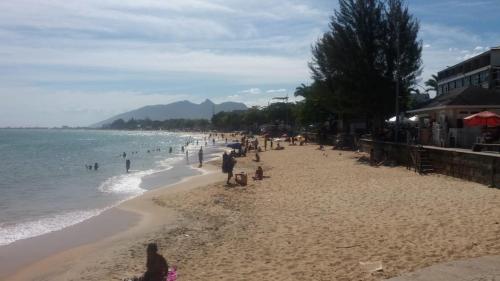 a group of people on a beach near the water at Pousada Bartrô in Rio das Ostras