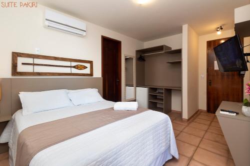 a bedroom with a large bed and a flat screen tv at Pousada Kia Ora Bombinhas in Bombinhas