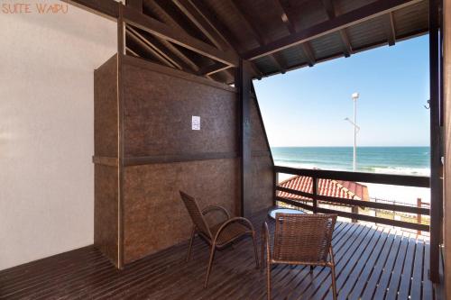 a balcony with two chairs and a view of the ocean at Pousada Kia Ora Bombinhas in Bombinhas