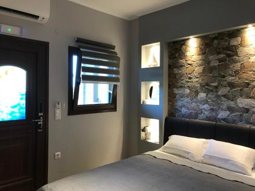 a bedroom with a bed and a stone wall at Anna - Tsiara paradise studios in Vourvourou