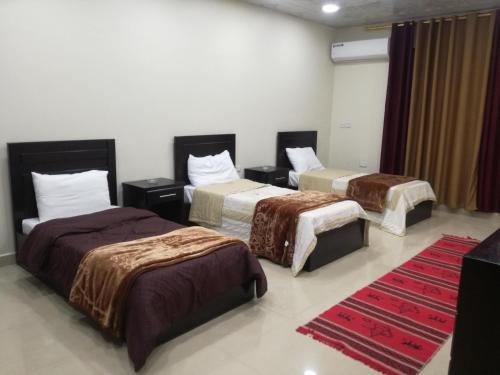 a hotel room with three beds and a red rug at Petra Crystal hotel in Wadi Musa