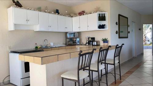 a kitchen with white cabinets and bar stools at Villa Paraíso in La Ventana
