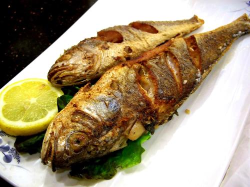 two fish on a white plate with a lemon at Forellenhof in Siegsdorf