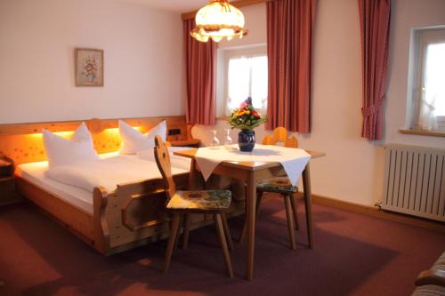 a bedroom with a bed and a table and chairs at Forellenhof in Siegsdorf