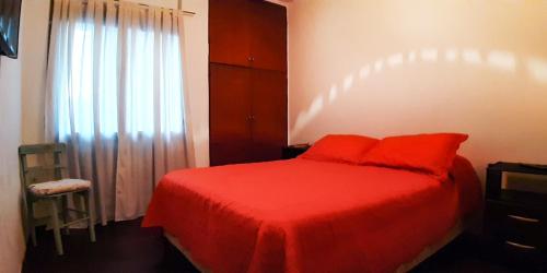 1 dormitorio con cama roja y ventana en Departamento amplio y comodo zona centro en Córdoba
