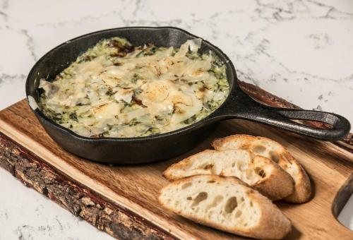 a pan of food on a cutting board with bread at Hotel Indigo - Birmingham Five Points S - UAB by IHG in Birmingham