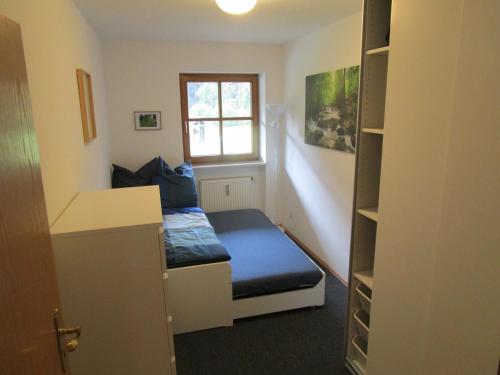 ein kleines Zimmer mit einem Bett und einem Fenster in der Unterkunft Hammerhaus-Apartment 3 in Siegsdorf