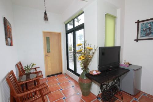 a living room with a television and a vase with flowers at Mandheling B&B in Jian