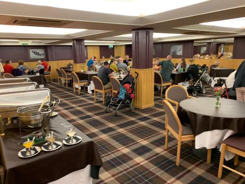 um restaurante com mesas e pessoas sentadas às mesas em Cross Keys Hotel, Kelso em Kelso