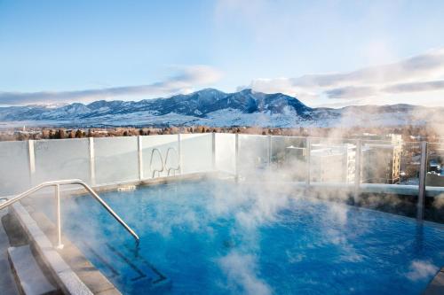 a hot tub with snow covered mountains in the background at Kimpton - Armory Hotel Bozeman by IHG in Bozeman