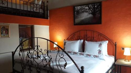 a bedroom with a white bed with an orange wall at Ipekyolu Garden in Avanos