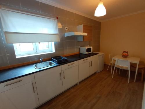 a kitchen with white cabinets and a sink and a table at Alojamento Dos Santos - Pinhão in Pinhão