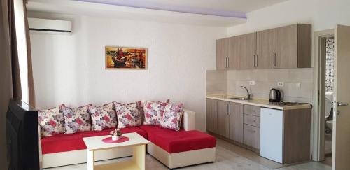 ein Wohnzimmer mit einem roten Sofa und einer Küche in der Unterkunft Apartments Ardoni in Ulcinj