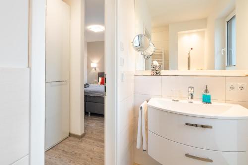 a white bathroom with a sink and a mirror at Appartement "Froschkönig" - Oase am Haff in Garz-Usedom
