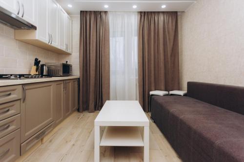 a kitchen and a living room with a couch and a table at Apart-smart on Kharkovskaya near Lavina 1 floor in Sumy