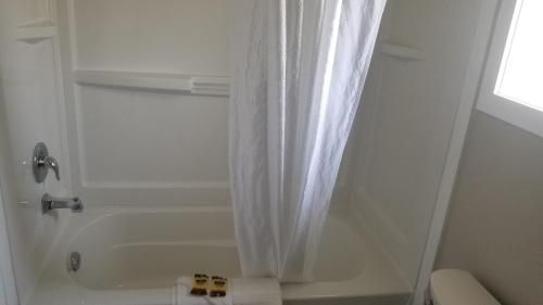 a bathroom with a shower with a white shower curtain at Sandy Beach Suites in Osoyoos