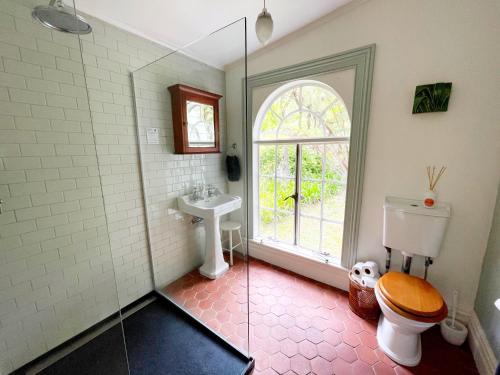 a bathroom with a toilet and a sink and a window at The Sanctuary- Waiheke Escapes in Oneroa