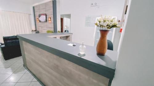 a vase with flowers on a counter in a room at Nacional Park Hotel Lages in Lages