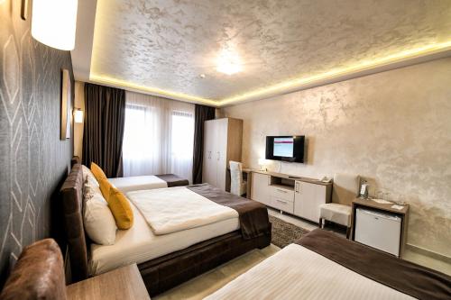 ein Hotelzimmer mit 2 Betten und einem TV in der Unterkunft Garnet Hotel & Event Centar in Ruma